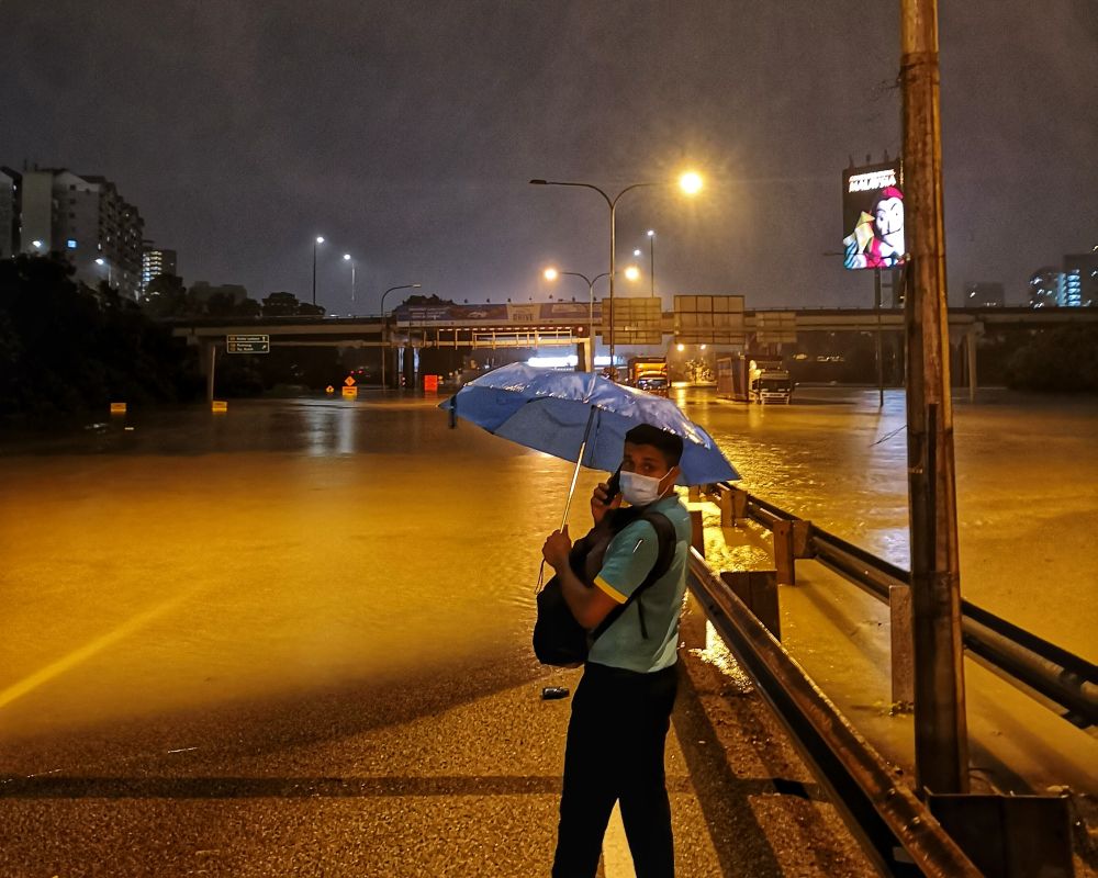 A man speaks on his phone as the Federal Highway is rendered impassable amid persistent rainfall in the Klang Valley December 18, 2021. u00e2u20acu2022 Picture by Shafwan Zaidonnn