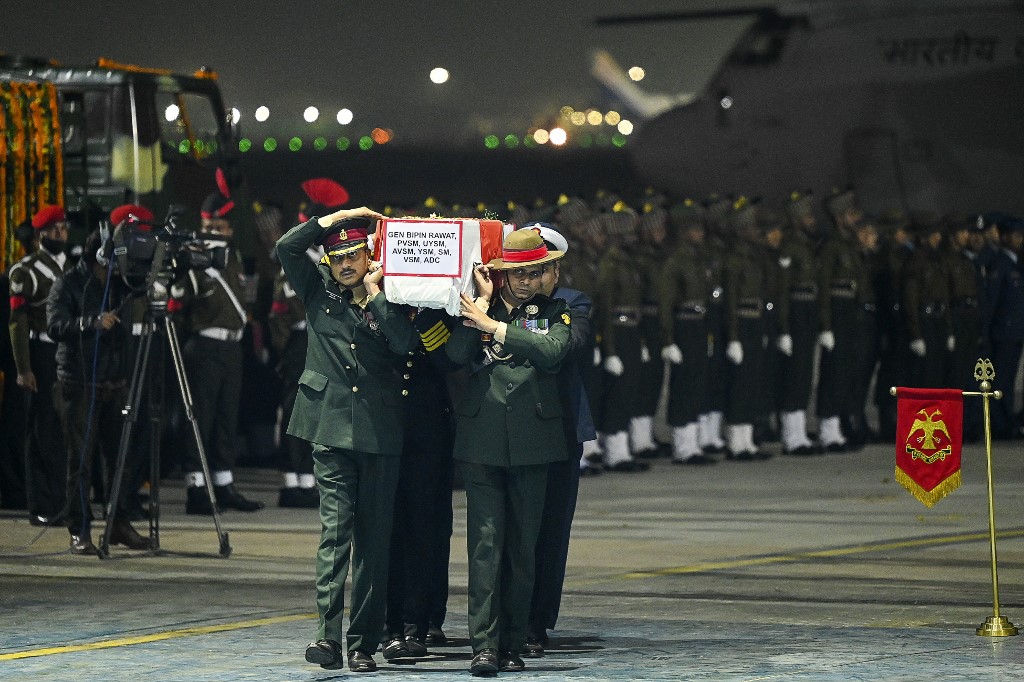 Army officers carry the coffins containing the mortal remains of India's defence chief General Bipin Rawat and other 12 victims who lost their lives in a helicopter crash a day earlier, during a tribute ceremony at Palam Air Force station in New Delhi on 