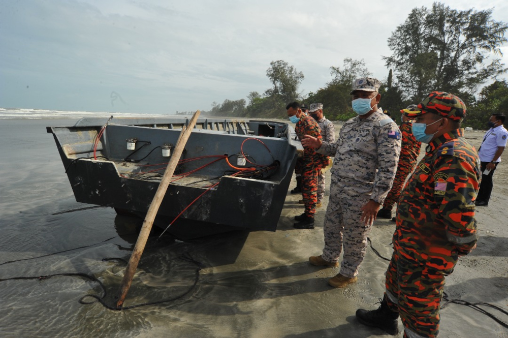 Johor Malaysian Maritime Enforcement Agency (MMEA) operations deputy director Simon Templer Lo Ak Tusa (centre) inspecting the capsized boat that was later retrieved on the Tanjung Balau beach in Kota Tinggi, December 15, 2021. u00e2u20acu201d Picture by Ben Tan