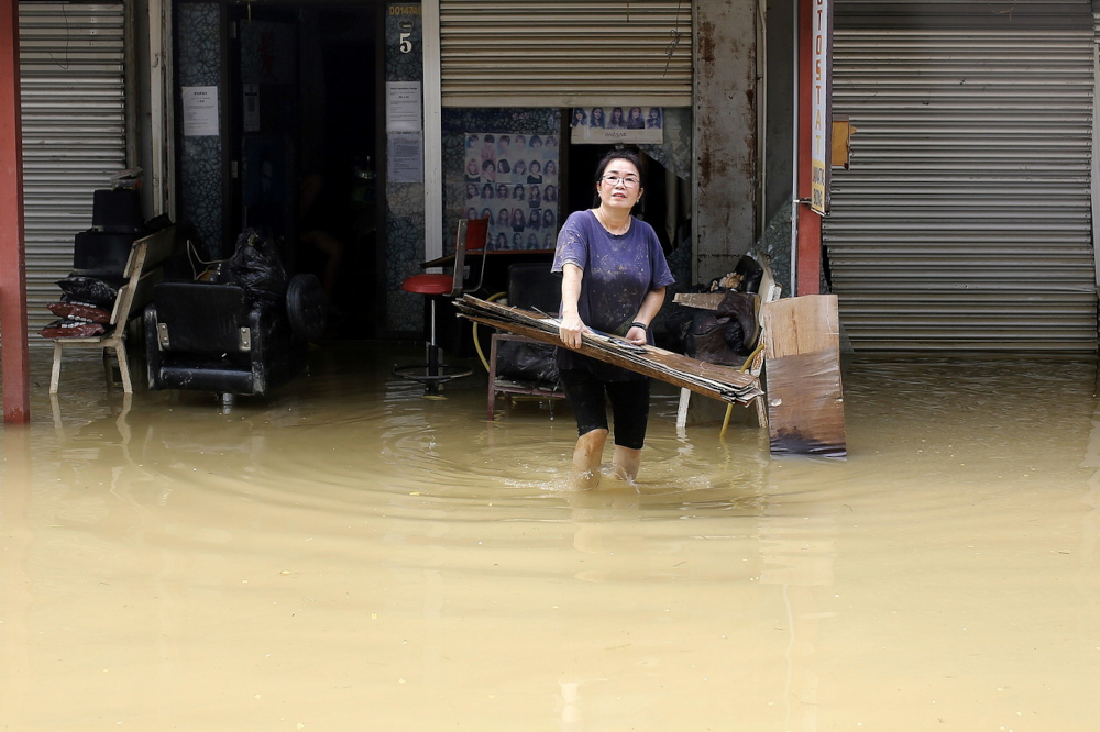 A woman carries debris from the flood out of her shop in Linggi, Negri Sembilan, December 20, 2021. u00e2u20acu201d Bernama pic 