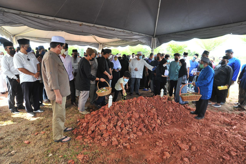 Close family members and friends of former Johor mentri besar Datuk Osman Sapian sprinkling rose water after his remains were laid to rest at the Ar Raudhah Islamic Cemetery in Mount Austin, Johor Baru. December 22, 2021. u00e2u20acu201d Picture by Ben Tan