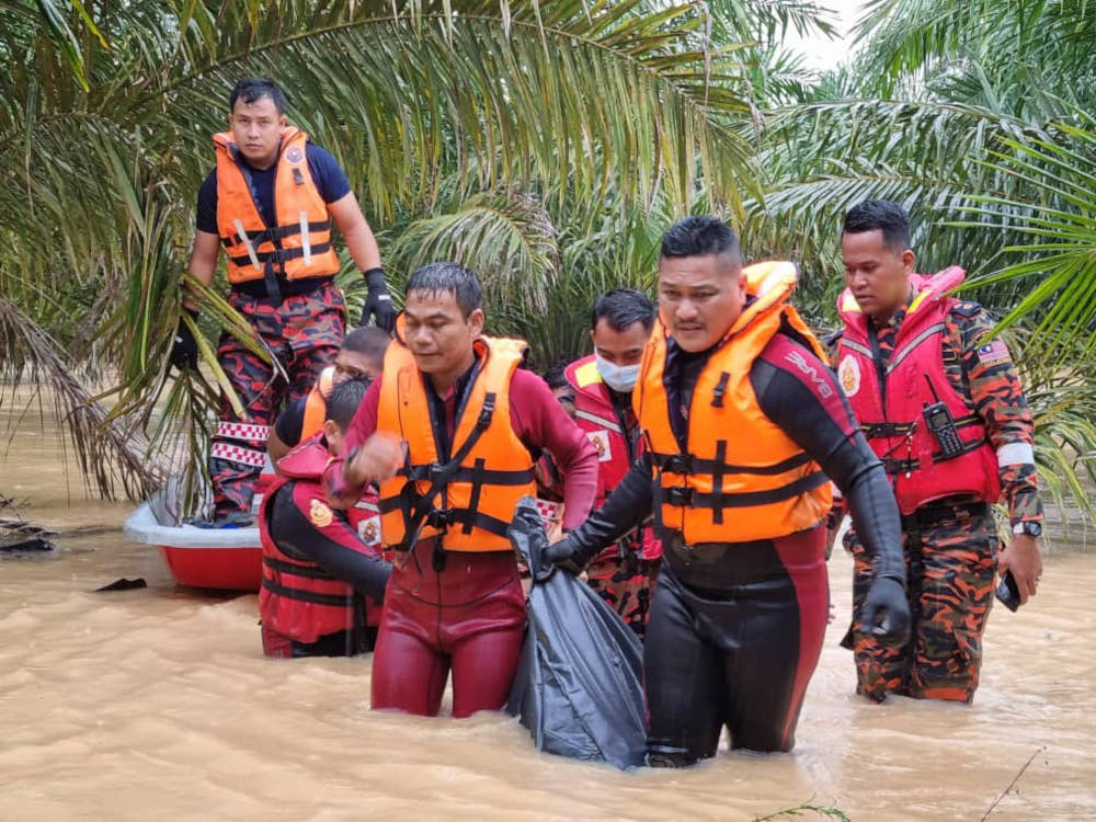 Firemen carry the body of a flood victim who fell from his motorcycle while trying to ride through floodwater near a Chinese cemetery in Gambang, Pahang, December 17, 2021. — Picture from Twitter from Fire and Rescue Dept via Bernama  