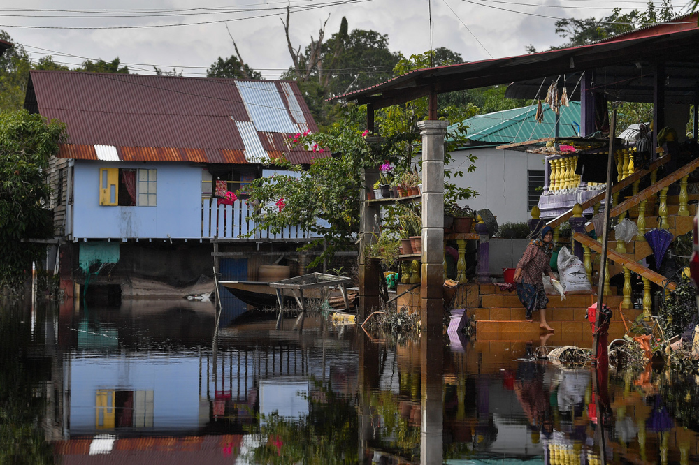 A woman cleans fish at her house which is still inundated with floodwater in Kampunag Baru Pulau Keladi near Pekan, Pahang, December 29, 2021. u00e2u20acu201d Bernama pic 