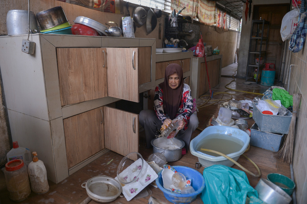 A woman cleans items in her kitchen following the flood in Puchong, December 22, 2021. u00e2u20acu201d  Picture by Miera Zulyana