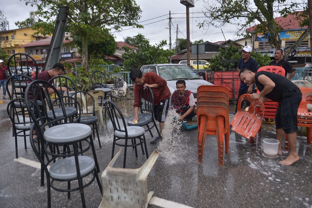 People are seen cleaning up an eatery as floodwaters recede in Puchong December 21, 2021. ― Picture by Miera Zulyana 