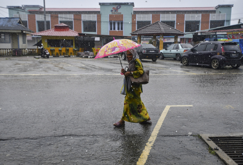 A woman walks in the rain in Rantau Panjang, Kelantan, December 29 2021. u00e2u20acu201d Bernama pic 