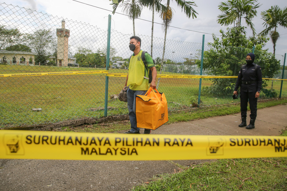 Election Commission (EC) personnel carry a ballot box to the Gita police station after early voting at Dewan Badminton Kompleks Perumahan Polis Tabuan Jaya in Kuching December 14, 2021. u00e2u20acu201d Picture by Yusof Mat Isa