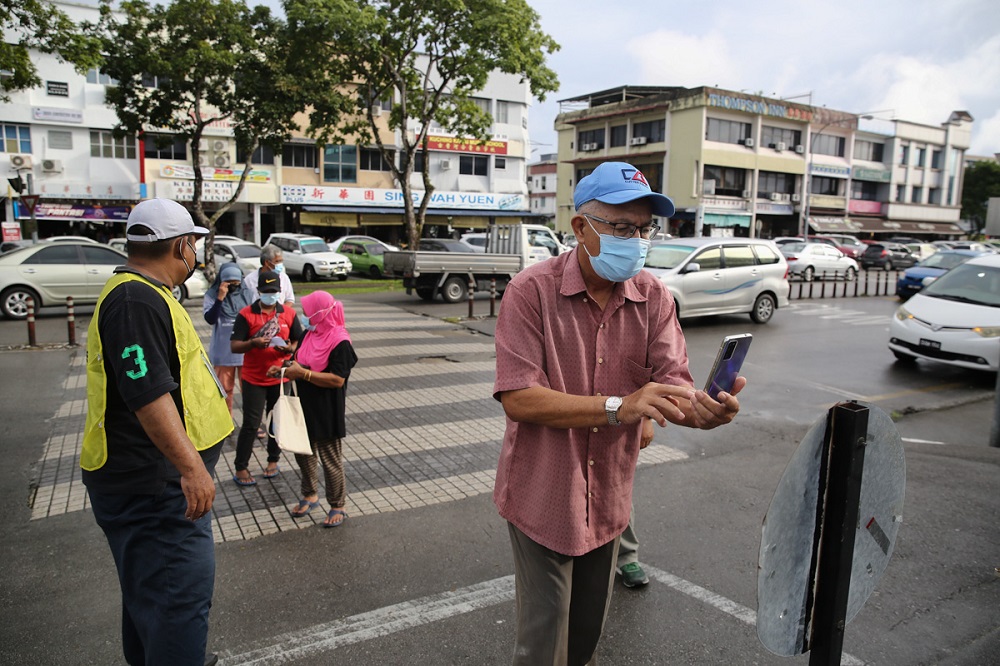 A man scans the MySejahtera QR code on his phone before entering the SJK Chung Hua No.4 polling centre in Kuching December 18, 2021. u00e2u20acu2022 Picture by Yusof Mat Isa