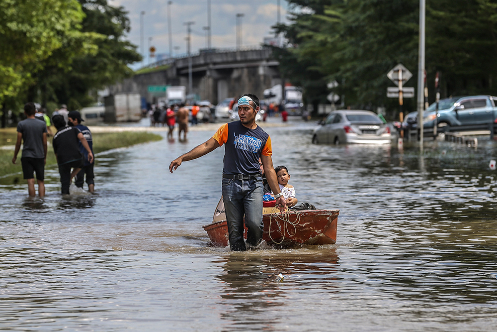 Flood victims seen wading through floodwaters in Taman Sri Muda, Shah Alam December 20, 2021. — Picture by Hari Anggara