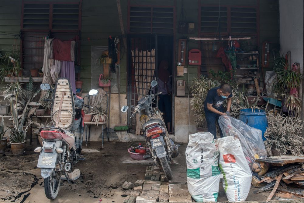 A man is seen cleaning up his home as floodwaters recede in Kampung Padang Jawa, Shah Alam December 22, 2021. u00e2u20acu2022 Picture by Shafwan Zaidon