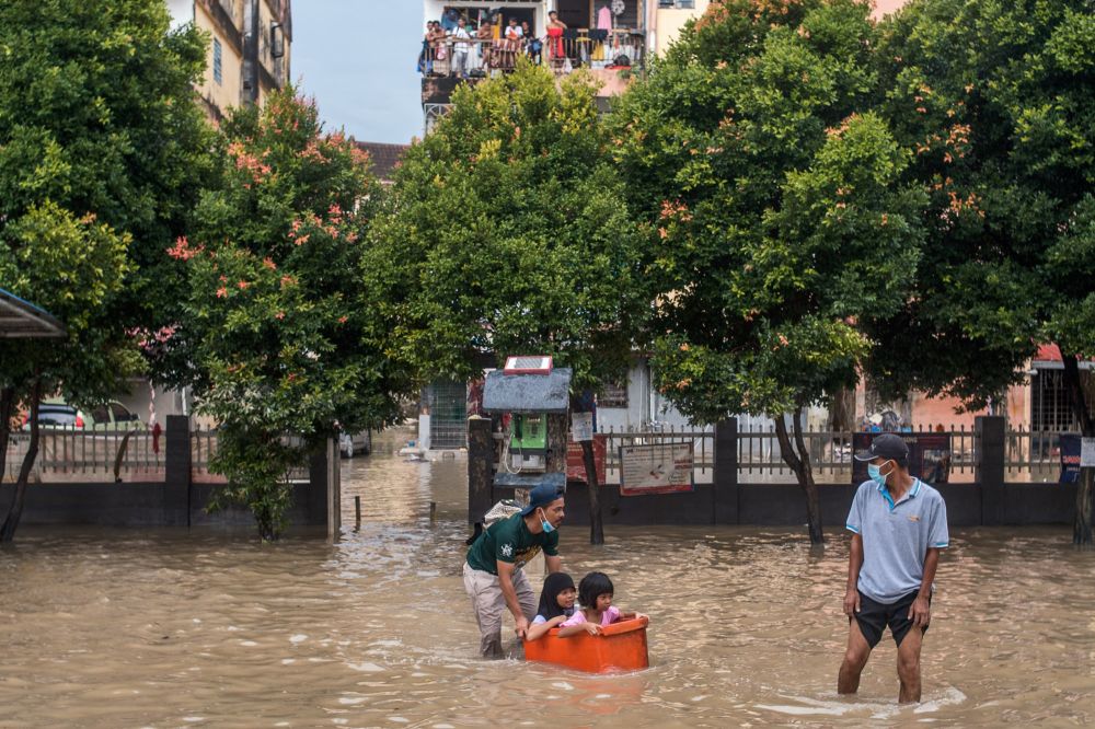 People wade through floodwaters in Taman Sri Muda, Shah Alam December 22, 2021. u00e2u20acu2022 Picture by Shafwan Zaidon