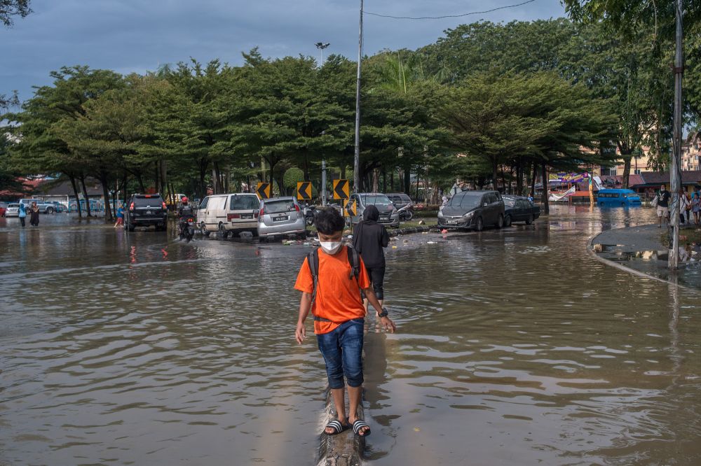 A boy wades through floodwaters in Taman Sri Muda, Shah Alam December 22, 2021. u00e2u20acu2022 Picture by Shafwan Zaidon