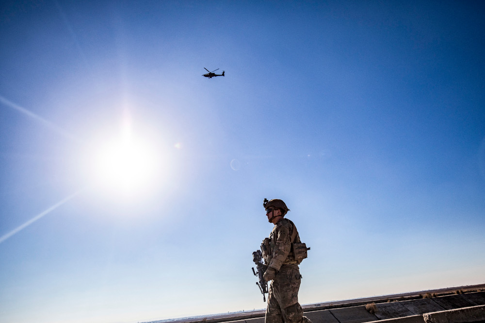A US AH-64 Apache attack helicopter flies above US soldiers patrolling along the frontlines between areas held by the Syrian Democratic Forces and Turkish-backed fighters near the village of Dardara in the countryside of Tal Tamr in Syriau00e2u20acu2122s north-easter