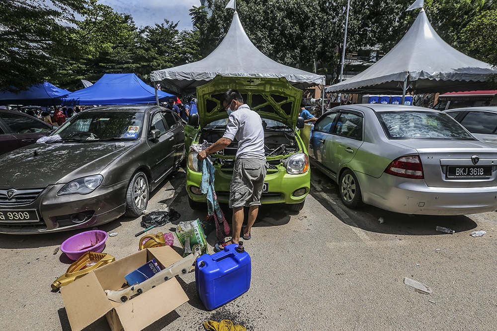 Flood victims are seen repairing their cars after a heavy flood in Taman Sri Muda in Shah Alam, Selangor December 21, 2021.