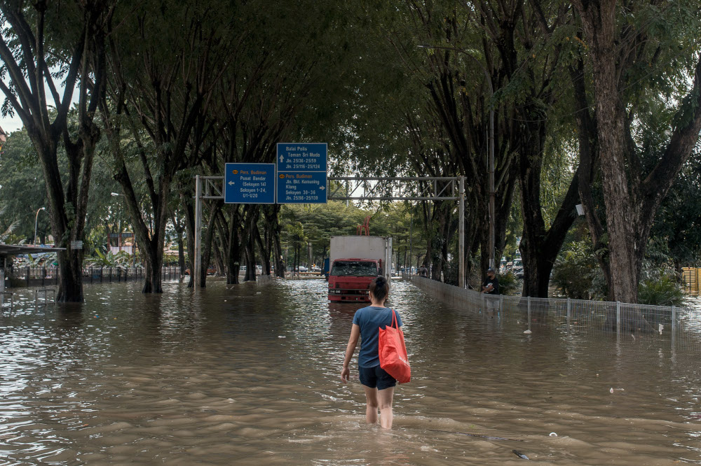 A woman is seen wading through floodwaters in Taman Sri Muda, Shah Alam December 22, 2021. — Picture by Shafwan Zaidon