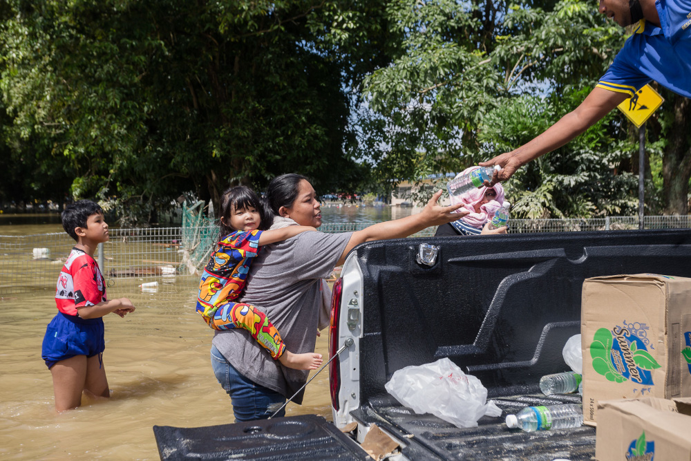  Flood victims receive drinking water from volunteers and rescuers at Taman Sri Muda, Shah Alam December 21, 2021. — Picture by Devan Manuel