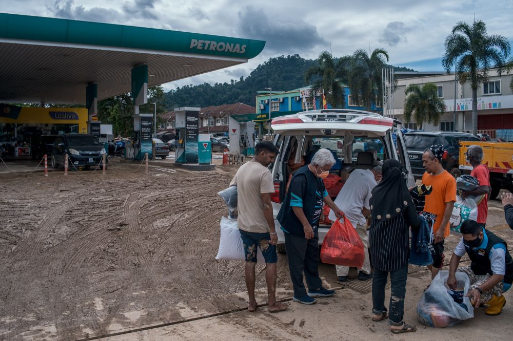 Members of an NGO distribute necessities to flood victims at Petronas Bukit Nanding, Hulu Langat December 21, 2021. — Picture by Shafwan Zaidon