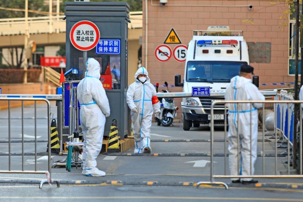 Workers in protective suits stand at an entrance to a university's residential area under lockdown following the coronavirus disease (Covid-19) outbreak in Xian, Shaanxi province, China December 20, 2021. u00e2u20acu201d China Daily pic via Reuters