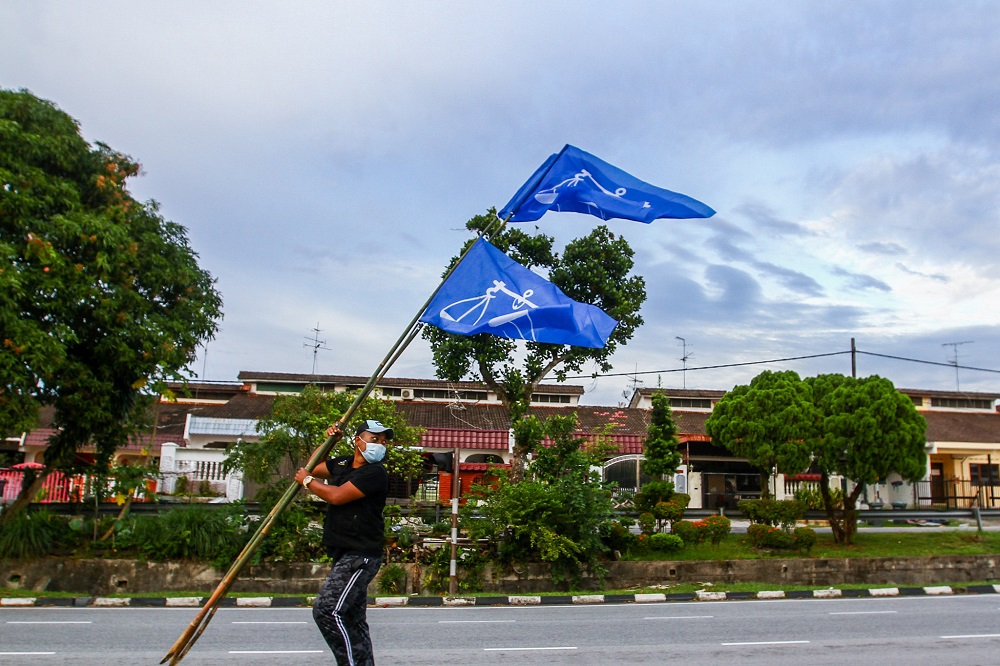 A man puts up Barisan Nasional flags along a road ahead of the Johor state election, in Johor Jaya February 28, 2022. u00e2u20acu201d Picture by Hari Anggara