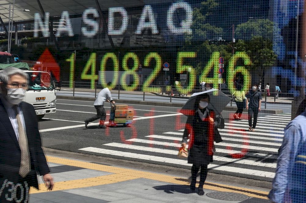 Pedestrians are reflected on an electronic board displaying Nasdaq Composite numbers in Tokyo, April 30, 2021. u00e2u20acu201d AFP pic