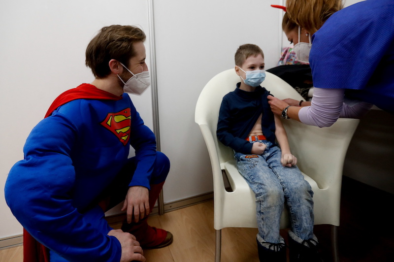 A medical staff member wearing a costume looks at a child who receives a shot of the Covid-19 vaccine at a mass vaccination center in Prague, Czech Republic January 8, 2022. u00e2u20acu201d Reuters pic