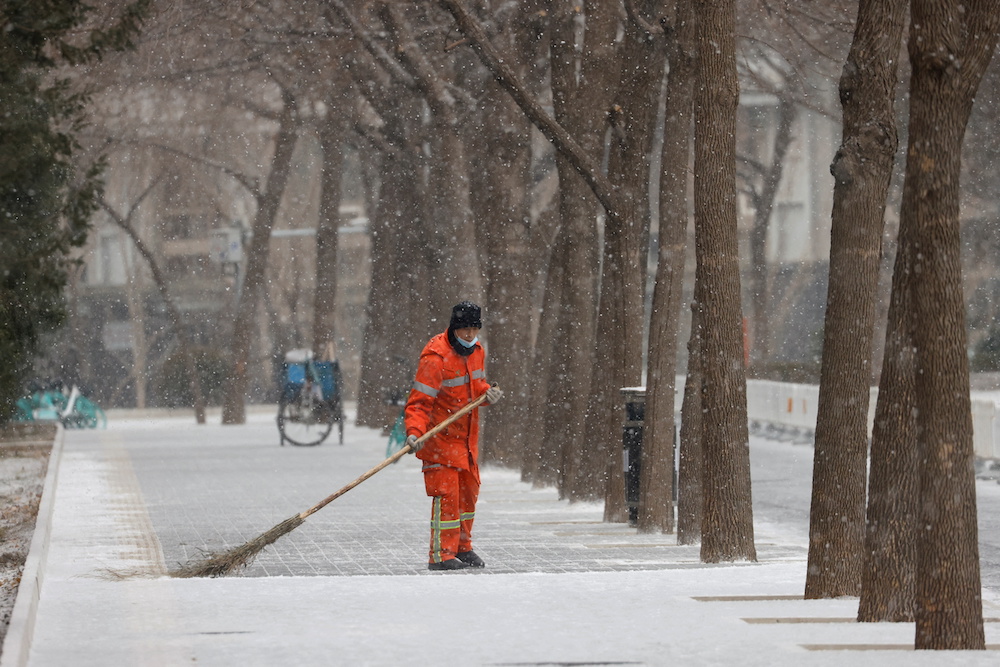 A municipal worker sweeps snow off a street amid snowfall in Beijing, China January 20, 2022. u00e2u20acu201d Reuters pic