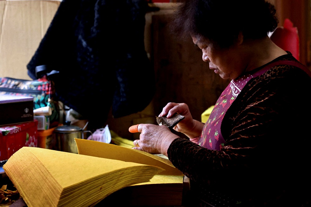 A staff member pastes a thin piece of silver sheet onto joss paper ahead of Lunar New Year at Chen Kun-huei’s workshop in Miaoli, Taiwan January 20, 2022. — Reuters pic