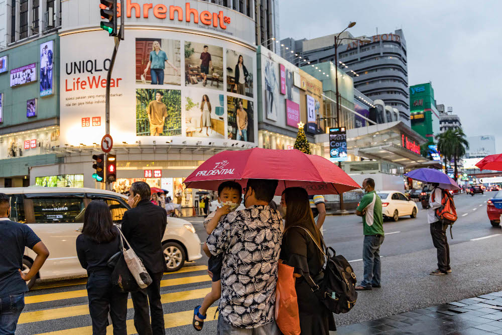 People hold umbrellas as they wait to cross at a traffic light during a rainy day in Kuala Lumpur January 2, 2022. u00e2u20acu201d Picture by Firdaus Latif