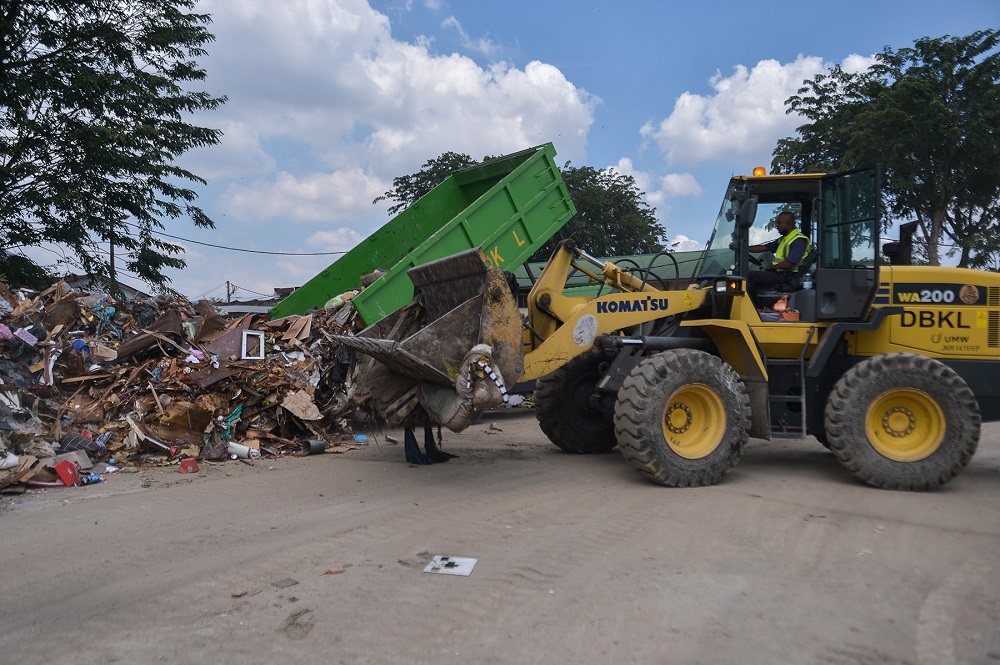 Workers clear piles of debris along a road following the floods at Taman Sri Muda in Shah Alam January 3, 2022. — Picture by Miera Zulyana