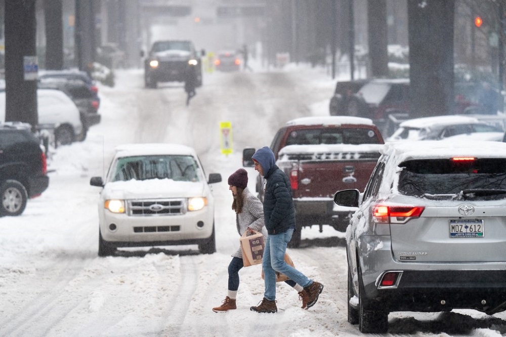 Pedestrians cross a street as motorists drive through the snow in Greenville, South Carolina January 16, 2022. u00e2u20acu201d AFP pic