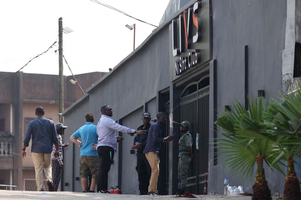 Passers-by walk past policemen standing guard at the entrance of the Livs night-club where a deadly fire occured in the Bastos district of Yaounde, on January 23, 2022. u00e2u20acu201d AFP pic