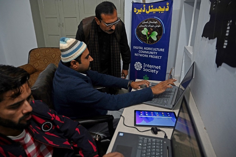 Aamer Hayat Bhandara, co-founder of Digital Dera, guides a farmer on how to check the weather at his office in Chak Twenty-six SP January 7, 2022. u00e2u20acu201d AFP pic