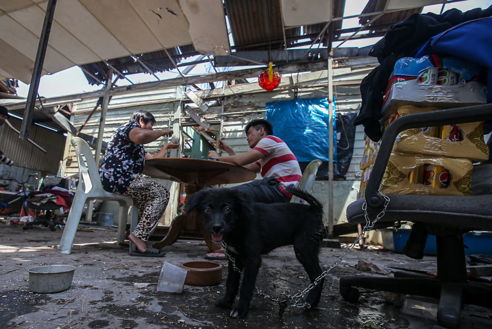 Kampung Tawas resident Cheah Kim and her son Cheng Man having their reunion meal at their home where the roof had been blown away by strong winds January 31, 2022. — Picture by Farhan Najib