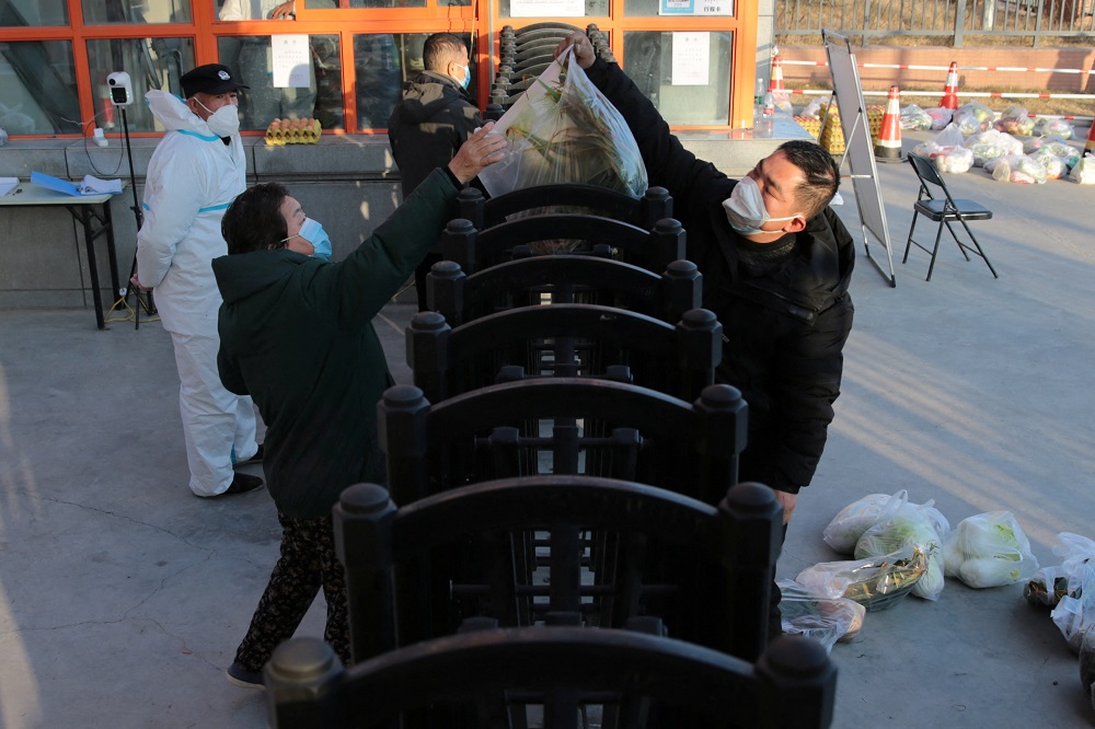 A worker delivers food supplies to residents at a residential compound under lockdown following the Covid-19 outbreak in Xian, Shaanxi province, China December 29, 2021. u00e2u20acu2022 cnsphoto via Reuters
