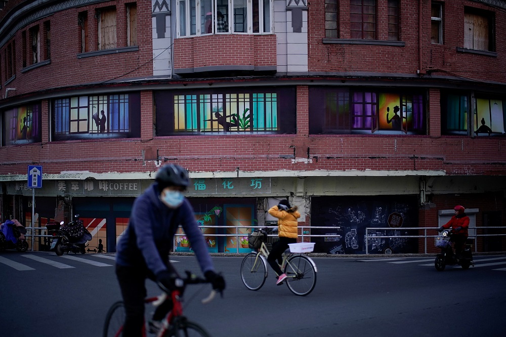 A person wearing a protective face mask rides a bike past a building in Shanghai, China January 20, 2022. u00e2u20acu2022 Reuters pic