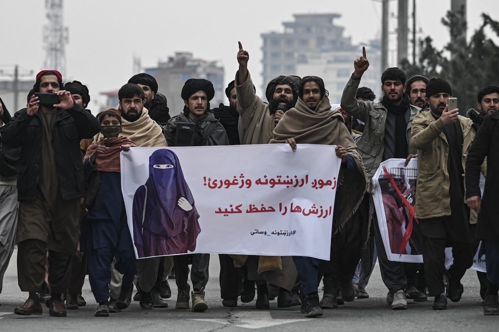 People stand along a street while holding banners during a demonstration to condemn the recent protest by the Afghan women's rights activists, in Kabul on January 21, 2022. u00e2u20acu2022 AFP picnnn