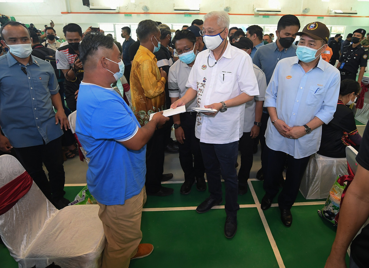 Prime Minister Datuk Seri Ismail Sabri Yaakob (centre) presenting assistance to a flood victim in Pitas District, Sabah, January 8, 2022. u00e2u20acu201d Bernama pic