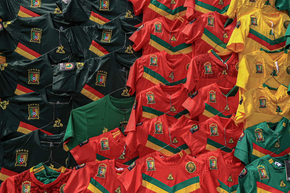 Cameroonian football jerseys hang along a wall at the central market in Yaounde, January 5, 2022. The Africa Cup of Nations (CAN) starts January 9, 2022 in Cameroon after a postponement in 2021. u00e2u20acu201d AFP pic