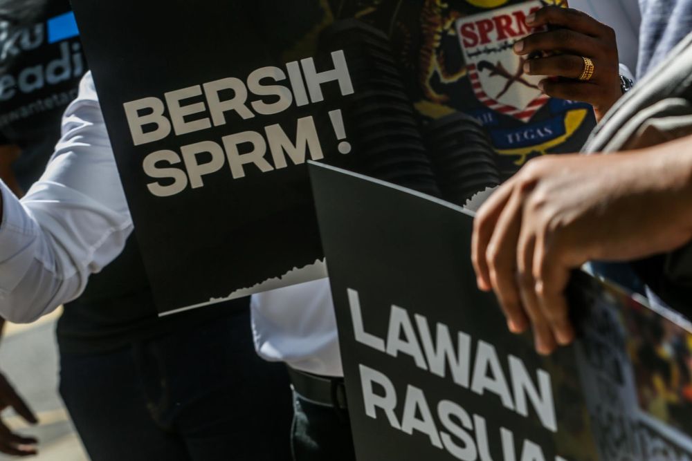 PKR members hold up placards protesting alleged corruption in MACC outside the Dang Wangi district police headquarters in Kuala Lumpur January 7, 2022. u00e2u20acu201d Picture by Hari Anggara