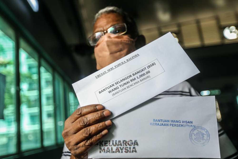 A recipient with his Bantuan Wang Ihsan (BWI) and Bantuan Selangor Bangkit (BSB) at Dewan Azalea, Taman Sri Muda, Shah Alam, January 11, 2022. u00e2u20acu201d Picture by Hari Anggara
