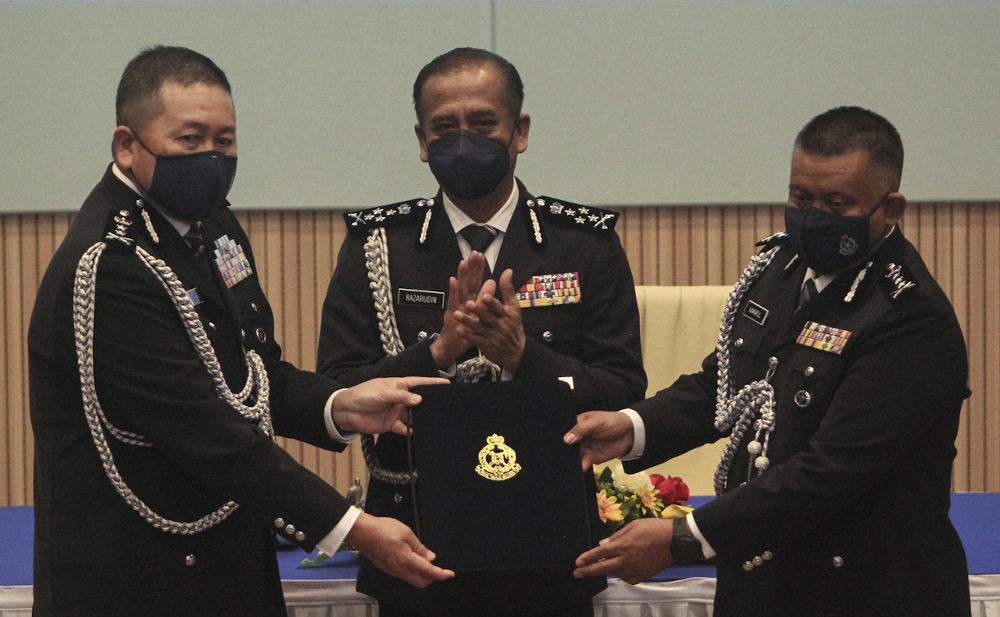 Deputy IGP Datuk Razarudin Husain@Abd Rasid (centre) watches the handover between Johor acting police chief Datuk Khaw Kok Chin (left) and the new Johor police chief Datuk Kamarul Zaman Mamat in Johor Baru January 16, 2022. u00e2u20acu201d Bernama pic