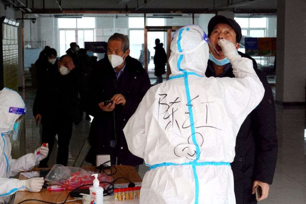 A medical worker in protective suit collects a swab sample from a man for nucleic acid testing, during another round of mass testing following the coronavirus disease outbreak in Xian, Shaanxi province, China December 27, 2021. u00e2u20acu201d cnsphoto via Reuters