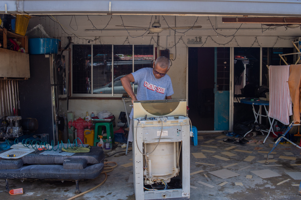 A man is seen inspecting a washing machine in flood-hit Taman Sri Nanding, Hulu Langat January 6, 2022. — Picture by Shafwan Zaidon