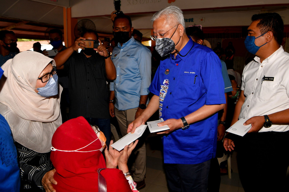 Prime Minister Datuk Seri Ismail Sabri Yaakob chats with flood victims while presenting a donation of RM1,000 during his visit to the temporary evacuation centre (PPS) at Sekolah Kebangsaan Gangsa, January 4, 2022. u00e2u20acu201d Bernama pic 