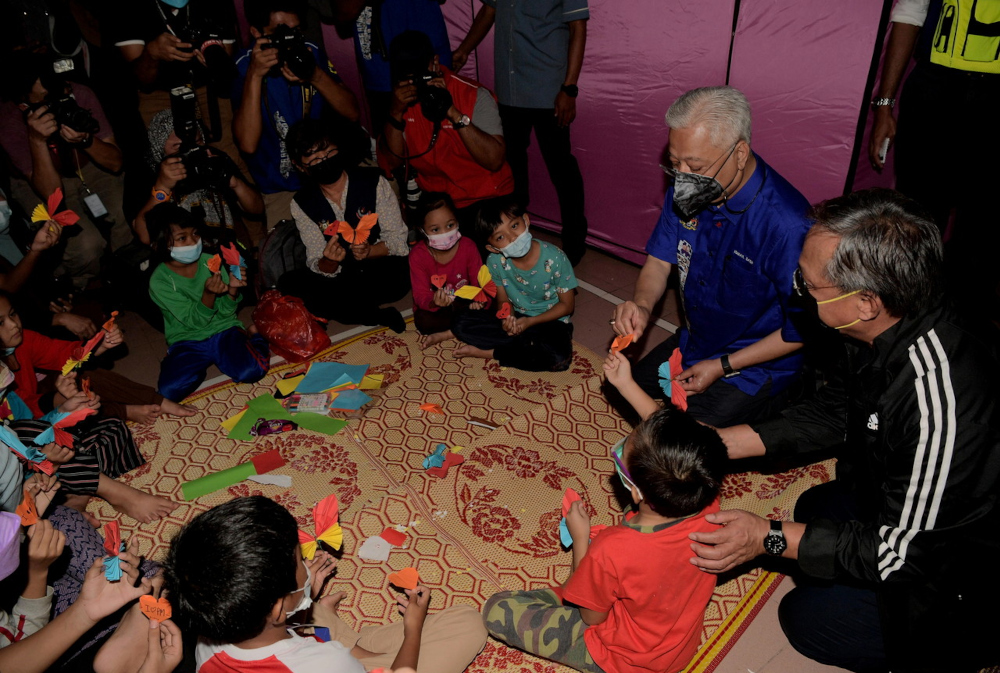 Prime Minister Datuk Seri Ismail Sabri Yaakob and Johor MB Datuk Hasni Mohammad talk to young flood victims housed at a temporary centre in Dewan Kampung Tandong in Segamat, Johor, January 4, 2022. u00e2u20acu201d Bernama pic 