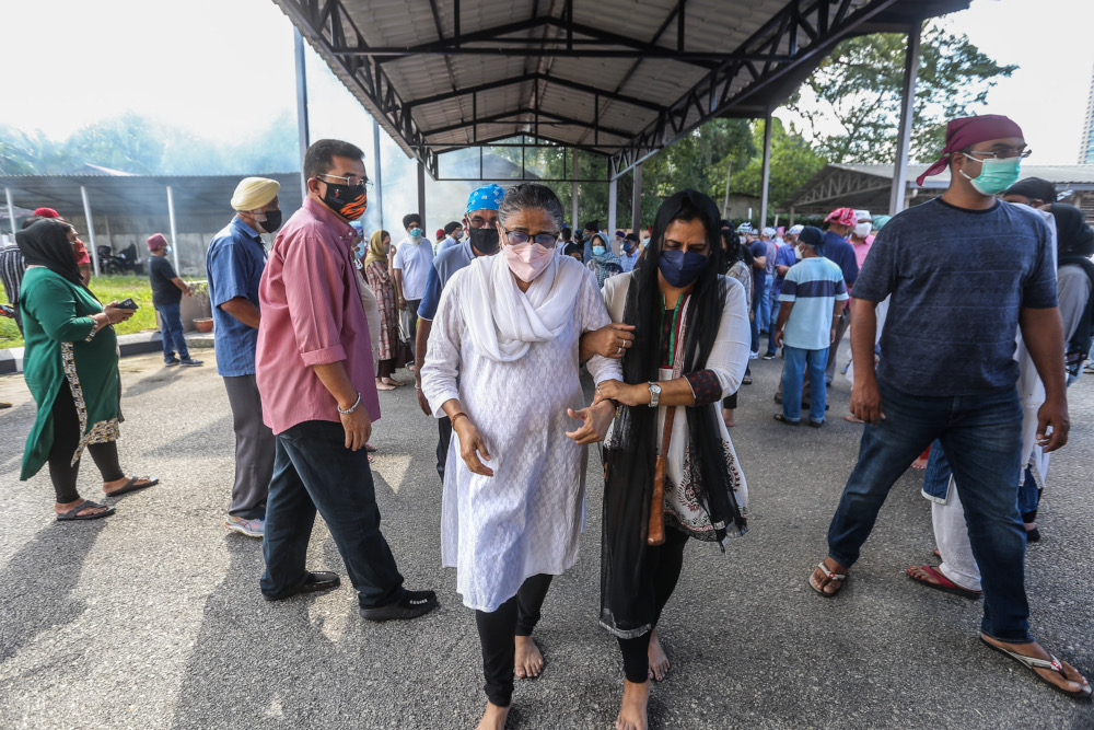 Shebby Singh’s wife, Harbans Kaur (in white) is held by a relative during the cremation ceremony in Shamshan Bhoomi Hall, Kuala Lumpur January 14, 2022. — Picture by Hari Anggara