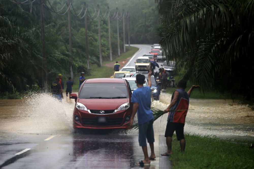 People are seen directing traffic as vehicles brave floodwaters in Tampin, Negri Sembilan January 2, 2022. u00e2u20acu201d Bernama pic