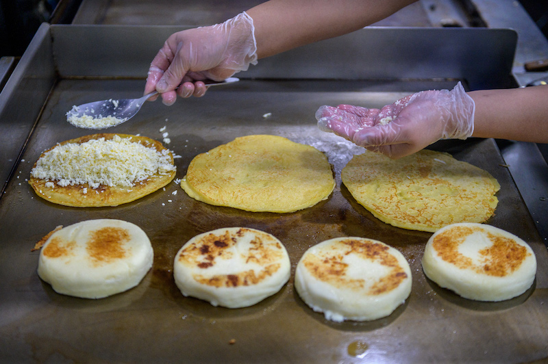 A cook prepares arepas in the kitchen of the Arepa Lady restaurant in the Queens borough of New York City January 27, 2022. — AFP pic