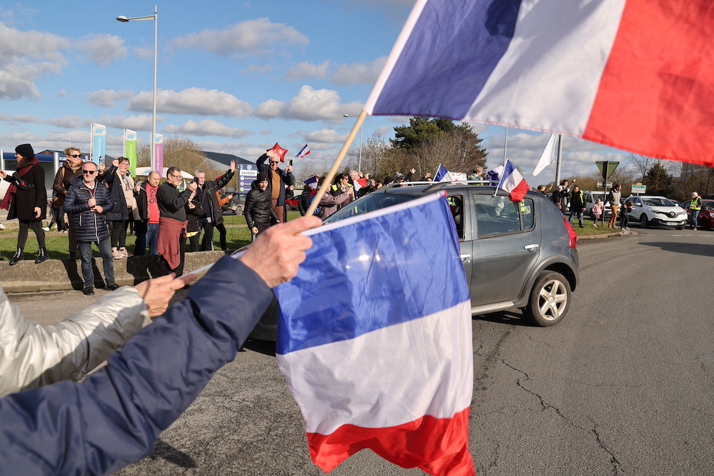 Supporters and members of the yellow vest movement hold French national flag on a parking lot of a shopping centre in Longueau as they cheer French anti-Covid restrictions car drivers during their u00e2u20acu02dcConvoi de la liberteu00e2u20acu2122 (The Freedom Convoy), February 