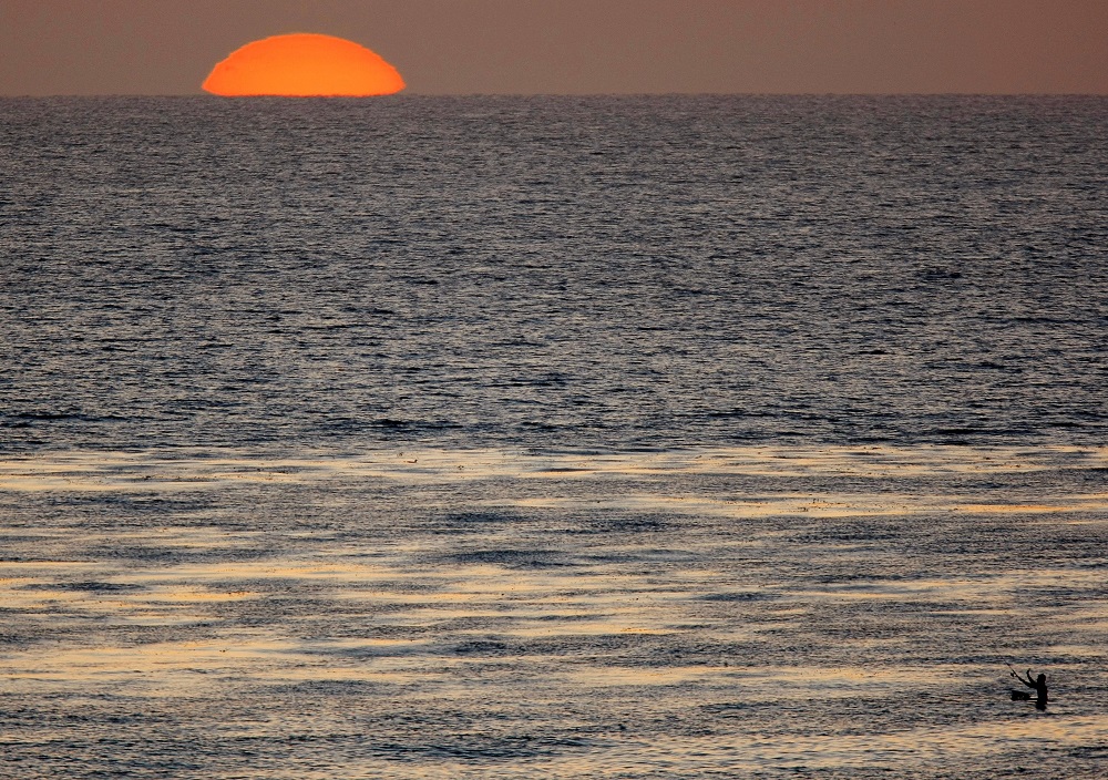 The sun sets as a fisherman casts his line in the Pacific Ocean while sitting on a surfboard off the coast of Cardiff, California April 1, 2008. u00e2u20acu201d Reuters pic